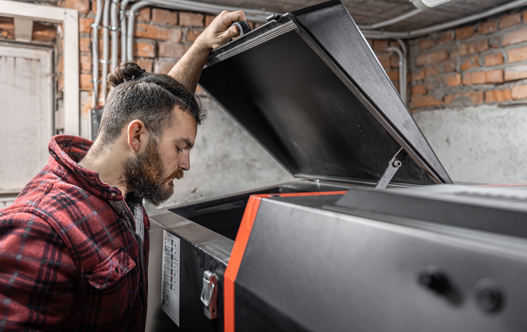 The man looking into a boiler on solid fuel in the room with pellets.