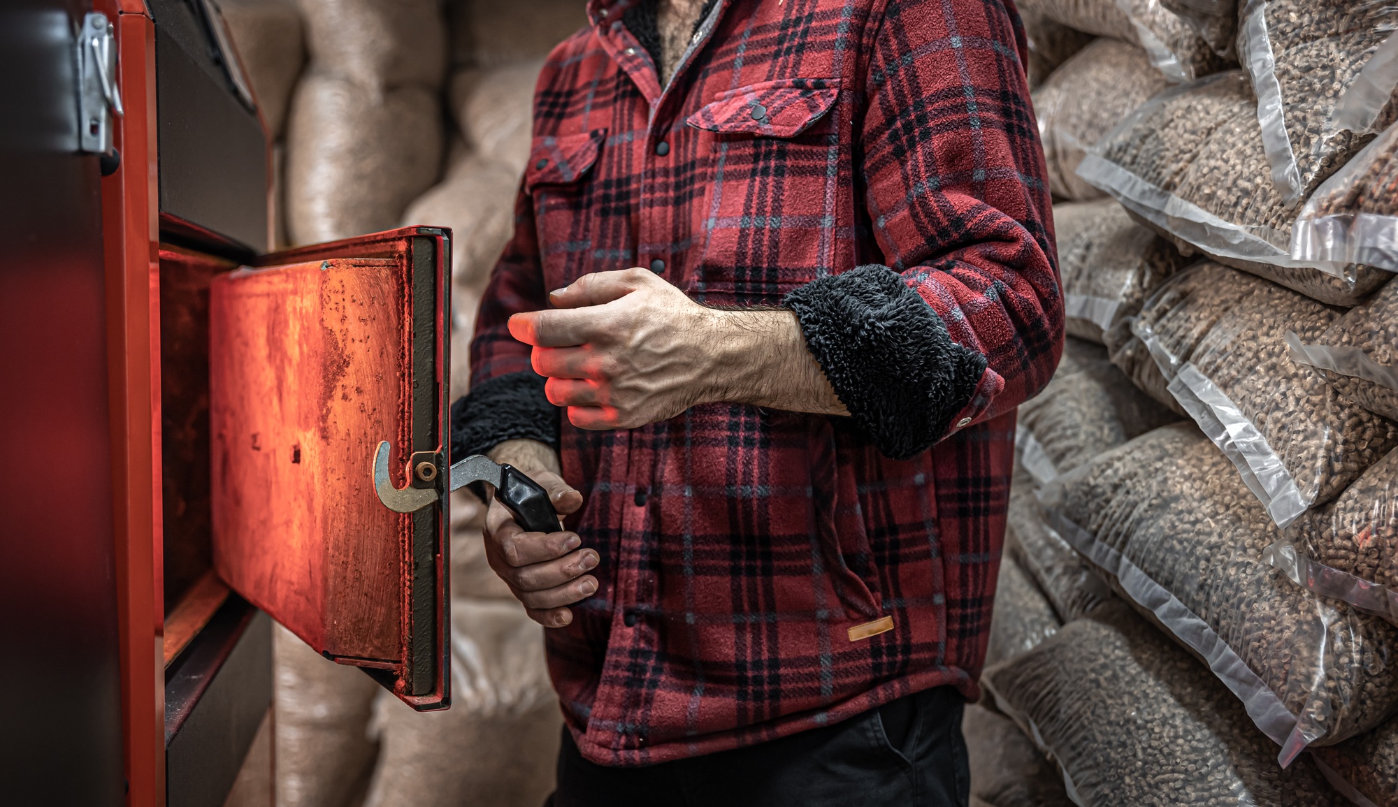 The man with a boiler on solid fuel, open door boiler with flames of fire.
